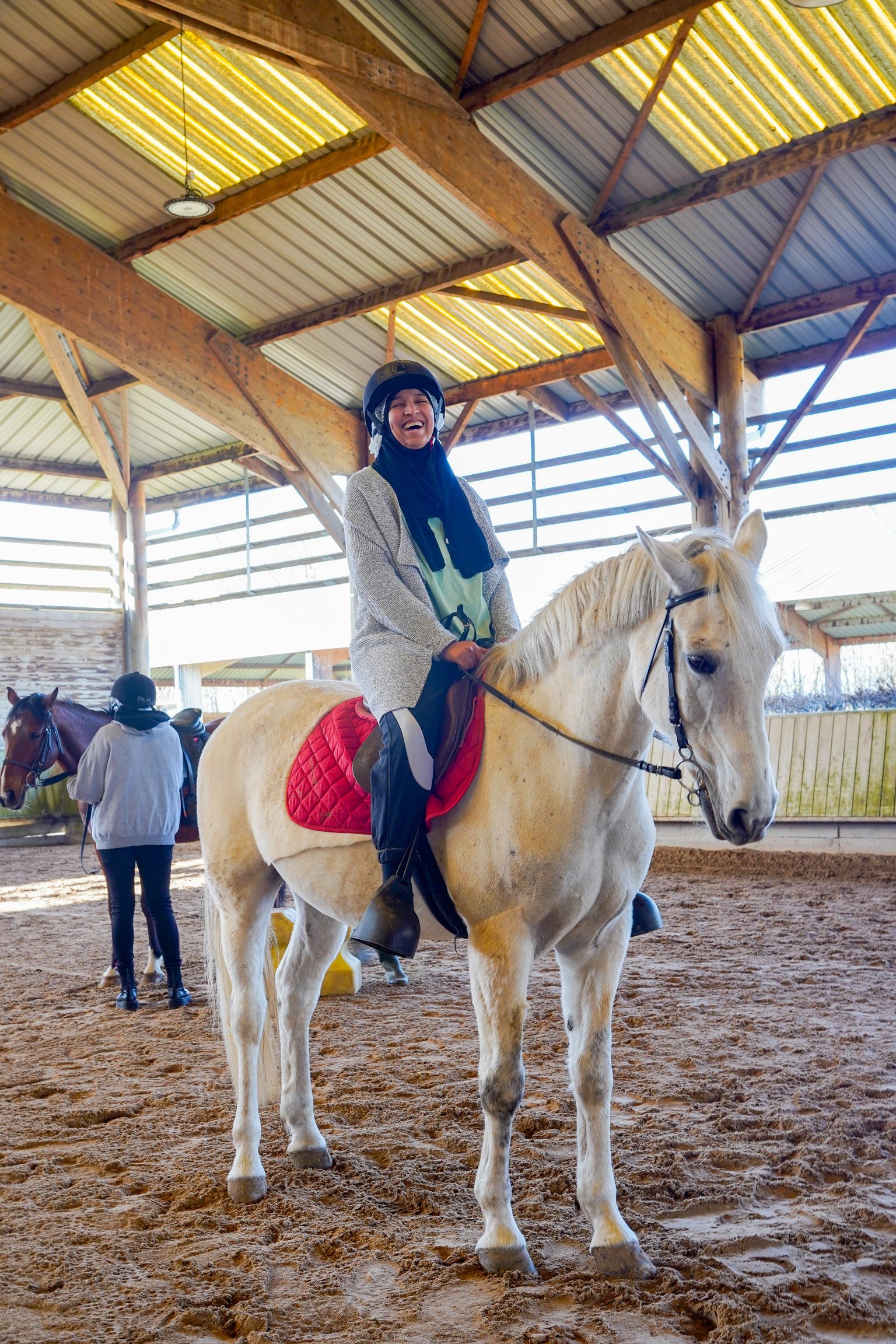 Cavalière souriante sur un cheval blanc dans le manège